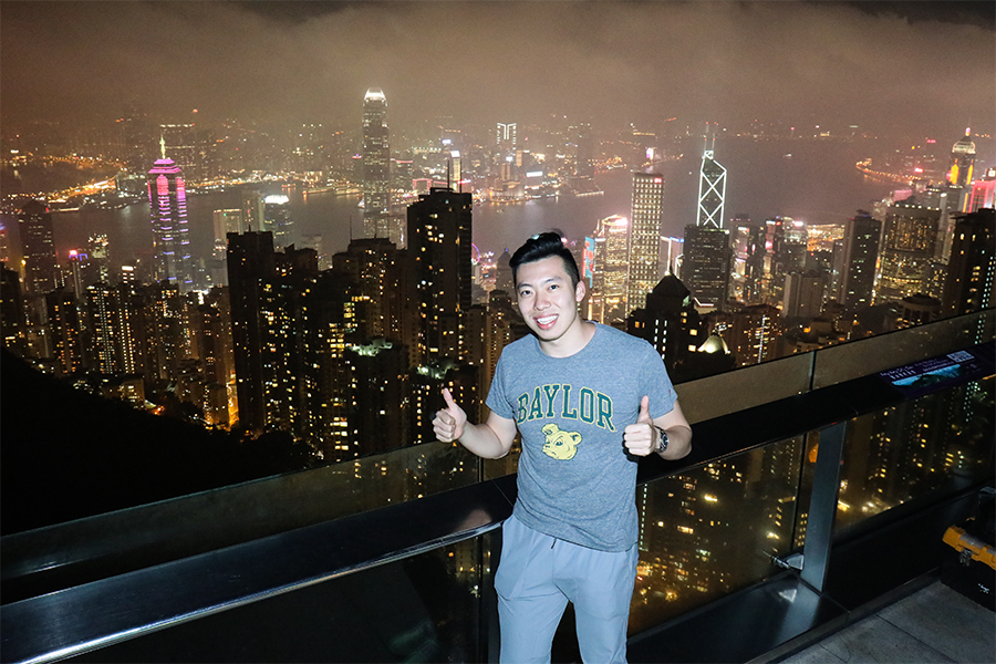 A person standing on a balcony overlooking a city at night.