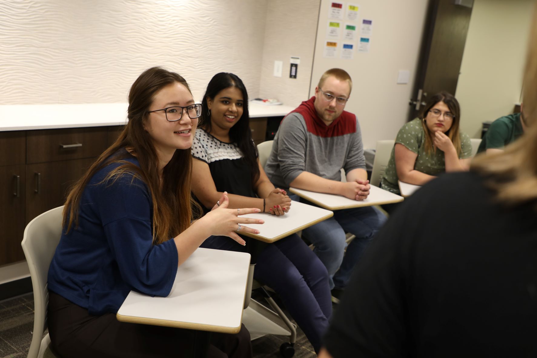 students sitting at desks talking in classroom
