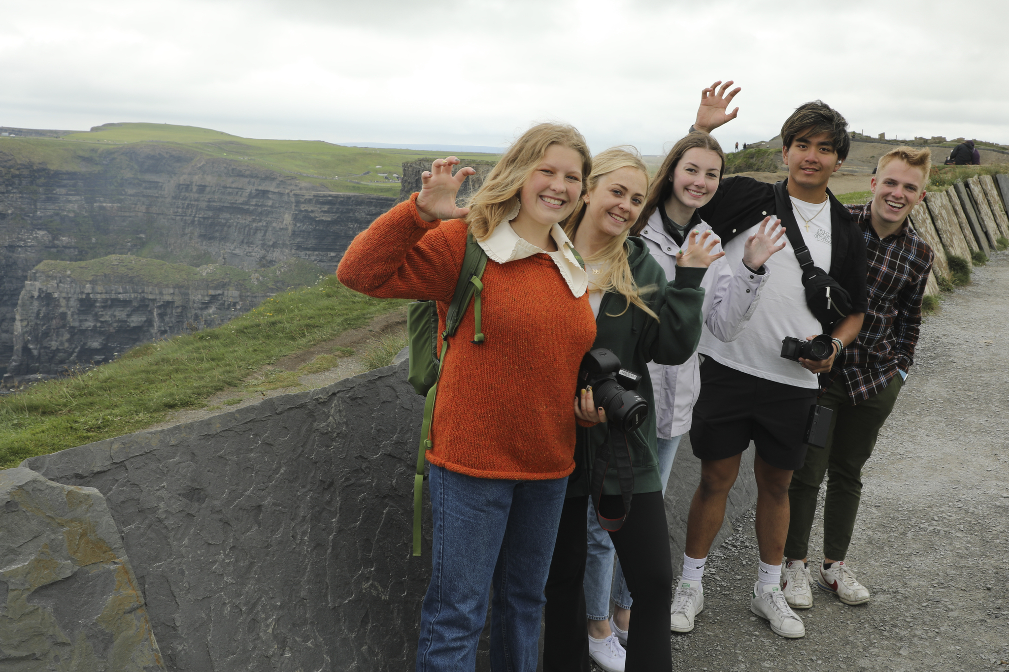 A group of people posing beside a cliff.