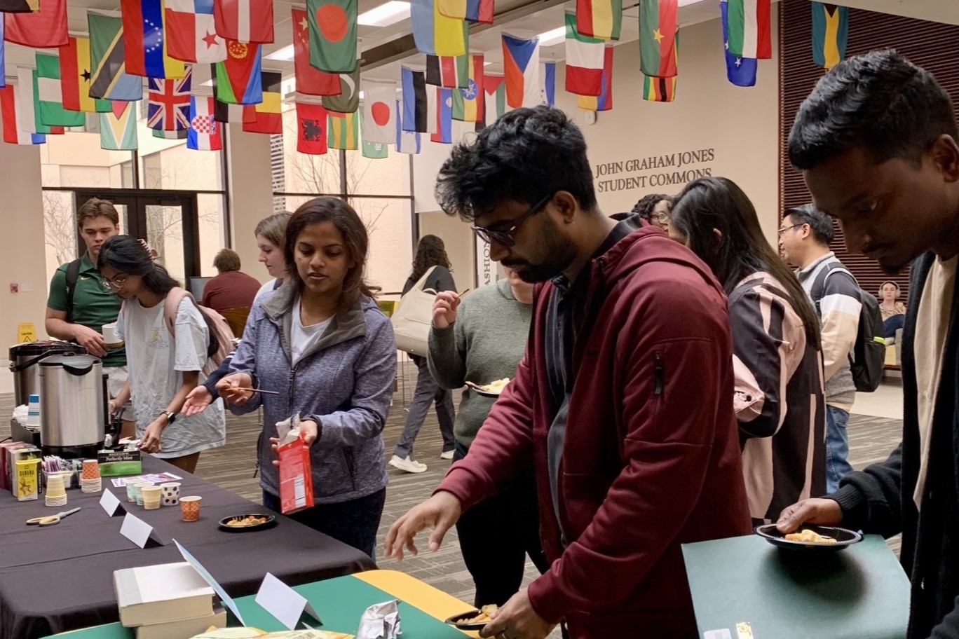Students in line at buffet in front of flags.