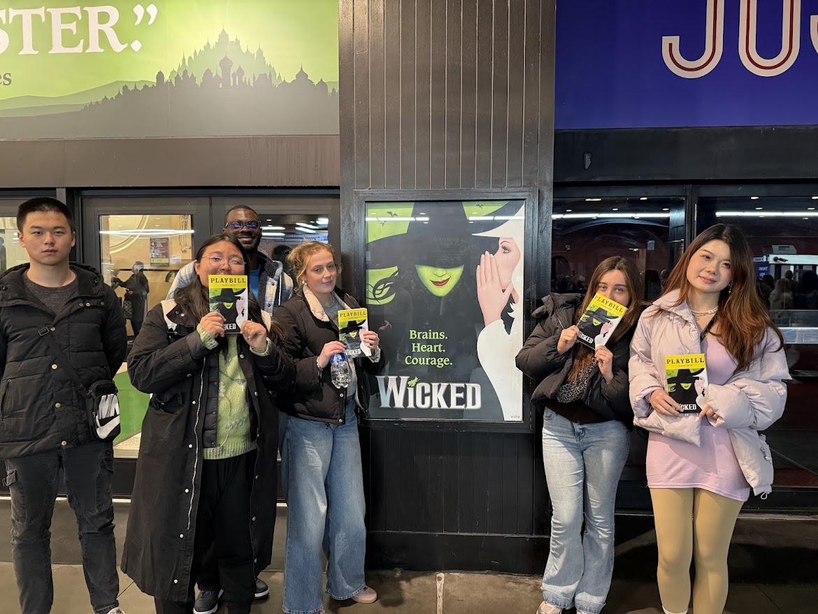 International students pose in front of the sign for the Broadway show "Wicked"
