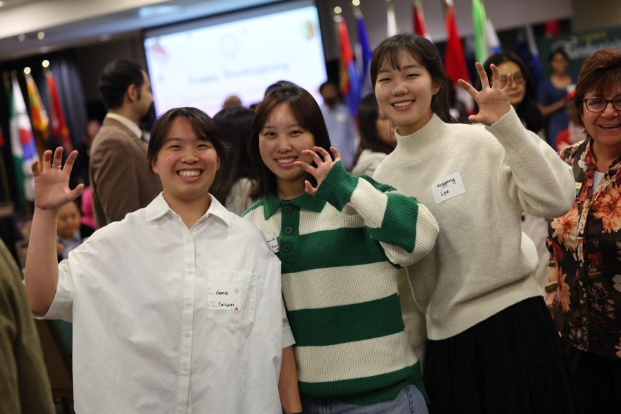 Chinese students at the international thanksgiving dinner hold up a "sic 'em".