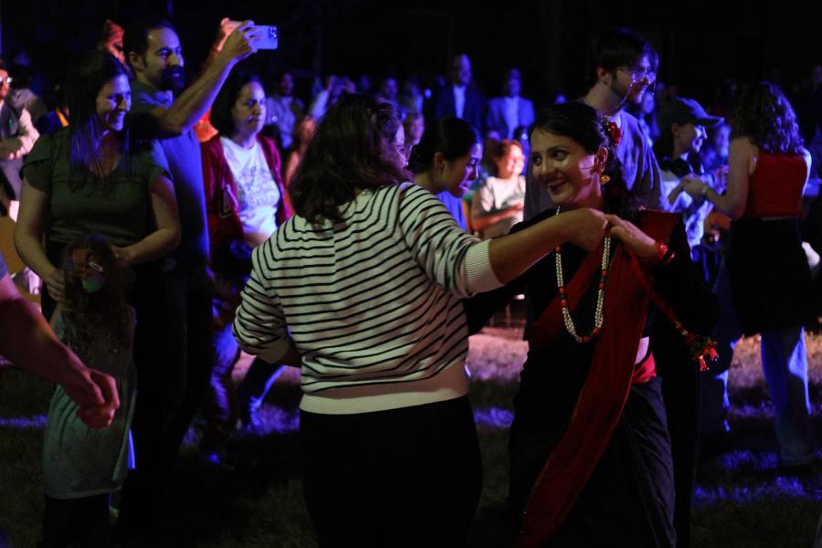 Two women dance in a crowd during the outdoor international fall festival. 