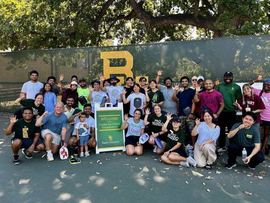 A group of Baylor students smiles together on the pickleball courts.